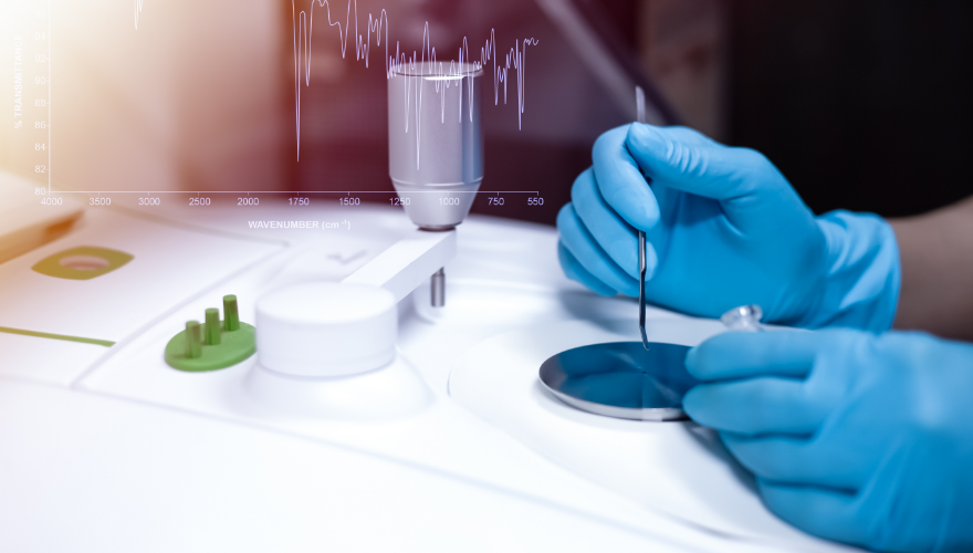 Person in blauen Handschuhen bedient ein wissenschaftliches Gerät mit Display.
